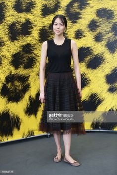 a woman standing in front of a yellow and black animal print wall with her hands on her hips