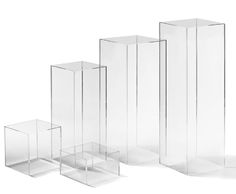 three tall clear vases sitting next to each other on a white surface with no one in them