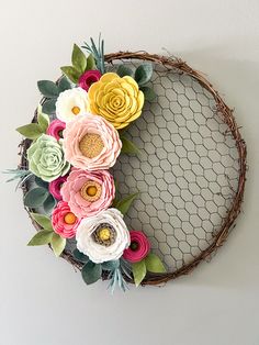 a wreath made out of paper flowers hanging on the side of a wall next to a chicken wire net