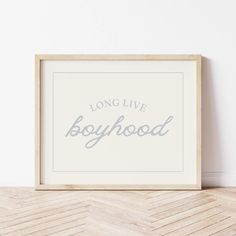 a wooden frame with the words long live boyhood in grey on it, against a white wall