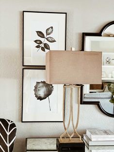 a lamp sitting on top of a wooden table next to a mirror and framed pictures