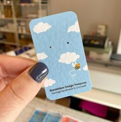 a person holding up a business card with clouds on it