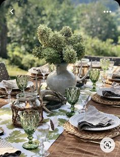 an outdoor table set with place settings and flowers in a vase on the centerpiece