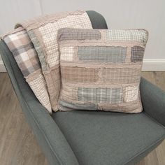 two pillows sitting on top of a chair in front of a white wall and wooden floor