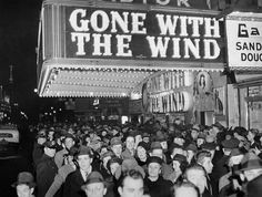 an old black and white photo of people in front of a theater sign that says gone with the wind