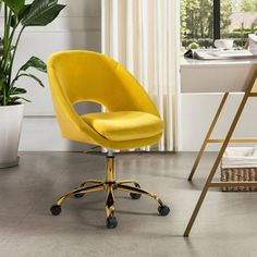 a yellow office chair sits in front of a desk with a laptop on it and a potted plant next to it