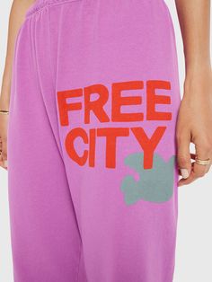 a person wearing pink sweatpants with the words free city printed on them