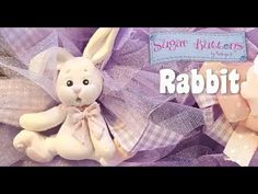 two stuffed animals sitting next to each other on top of purple fabric with the words sugar buttons rabbit