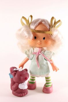 a doll with blonde hair holding a pink teddy bear