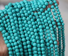 a hand holding a bunch of turquoise beads