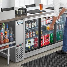 a man standing in front of a refrigerator filled with drinks