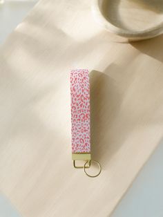 a pink and white animal print keychain sitting on top of a wooden table