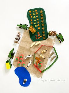 an assortment of toy animals and toys on top of a cloth covered table with a white background