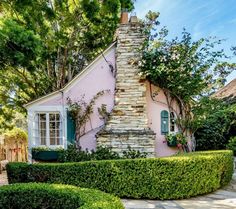 a pink house surrounded by hedges and trees