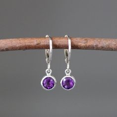 "Sweet faceted bright Purple Amethyst round stones are bezel set in small silver charms.  These dangle from silver lever back huggie hoops.  These classic earrings are perfect for any age and any occasion!  Please note these charms are small.  These earrings are also available in a smaller size... www.etsy.com/listing/710543884/amethyst-earrings Amethyst bezels: 6mm Silver charms: 6x9mm Silver huggie hoop: 1x12mm Total length of earrings: 7/8\" Length is approximate.  All silver is sterling. As Classic Round Amethyst Earrings, Everyday Round Earrings With Bezel Setting, Gift Dangle Earrings With Bezel Setting, Round Earrings With Bezel Setting, Sterling Silver Dangle Earrings With Bezel Setting, Sterling Silver Earrings With Bezel Setting As Gift, Round Amethyst Gemstone Earrings, Sterling Silver Jewelry With Bezel Setting And Dangle Shape, Elegant Round Faceted Hoop Earrings