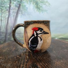 a coffee cup with a bird painted on it's side sitting on a wooden table