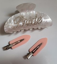 three pairs of hair clips sitting on top of a white table next to each other