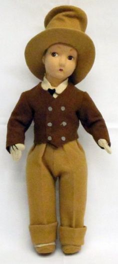 a doll with a brown outfit and hat on it's head is posed in front of a white background