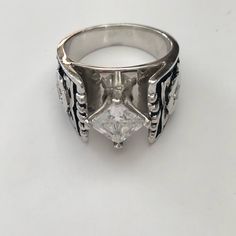 a silver ring with a white diamond in the center and black stripes around it, on a white background