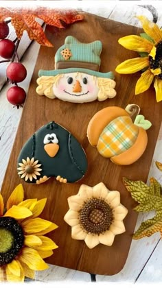 some decorated cookies are sitting on a cutting board with sunflowers and other decorations