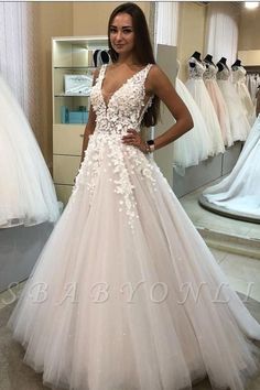 a woman standing in front of a mirror wearing a wedding dress with flowers on it