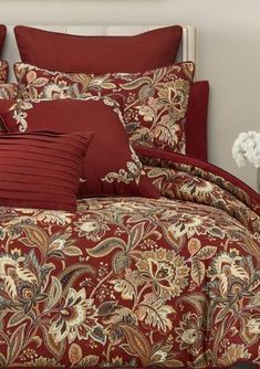 a bed with red comforters and pillows on it