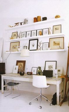 a white desk and chair in a room with many pictures on the wall above it