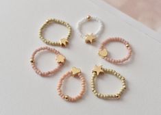 💍 These elegants Miyuki bead  rings are so stunning and chic, customized just for you or for someone you love ❣️ It is the perfect addition to your jewelry collection ❣️  Suitable for  kids (4-10 year old) and adults. ❣️Colours available :  Dusty pink  White  Khaki  ❣️High quality gold plated charms available: star, heart, flower, crown, bear ❣️ You can choose a single item, a set of 3 pcs, or 5 pcs   ❣️These rings are threaded by hand with jewelry elastic thread, so it will fit most sizes and Cute Beaded Rings For Gifts, Handmade Adjustable Stackable Rings, Trendy Handmade Adjustable Stackable Rings, Trendy Handmade Stackable Rings, Cute Spacer Beads For Jewelry Making, Cute Pink Jewelry With Spacer Beads, Adjustable Stackable Rings With Tiny Beads As Gifts, Pink Beaded Rings For Gift, Cute Pink Jewelry With Tiny Beads