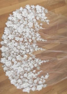 white flowers are wrapped in plastic on a wooden floor with a piece of clear cellophane