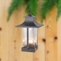 an outdoor hanging light with three lights on the top and one in the middle, against a wooden fence