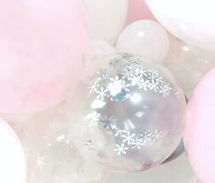 white and pink balloons with snowflakes on them are all over the place in this photo