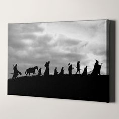 a black and white photo of people walking on a hill with horses in the background