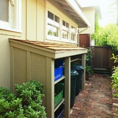 an outside view of a house with plants and trash cans