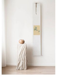 a vase sitting on top of a wooden table next to a white wall