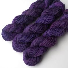 two skeins of purple yarn on a white surface