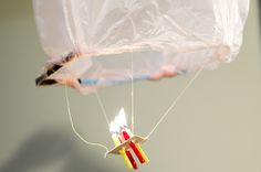 a kite shaped like a bird with two candles attached to it's wings and string