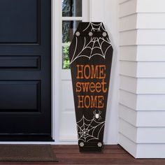 a black and orange sign that says home sweet home next to a door with spider webs on it