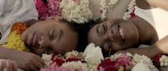 two women laying next to each other with flowers around them