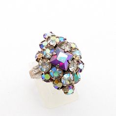 a multicolored diamond ring sitting on top of a white surface