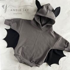 a baby's gray onesuit with black bats on the front and back, sitting on a marble surface