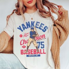 Step up to the plate in style with the "Vintage Baseball Team" Tee, showcasing iconic designs of your favorite baseball teams from the golden era of baseball. Crafted from premium fabric, this tee ensures both comfort and durability, making it perfect for honoring the rich history of America's favorite pastime. The vintage-inspired designs capture the nostalgia and heritage of classic baseball teams, bringing the spirit of the ballpark to your wardrobe. Whether you're cheering from the stands or Baseball Season Fan Apparel T-shirt With Graphic Print, Fan Apparel Baseball Jersey With Graphic Print, Collegiate Baseball Jersey With Graphic Print For Fans, Collegiate Cotton Baseball Jersey With Graphic Print, Fan Apparel Baseball Jersey With Crew Neck, Throwback Letter Print T-shirt For College, Baseball Jersey With Graphic Print For Game Day, Throwback Screen Print Tops For Baseball Season, Throwback Baseball Season Fan T-shirt