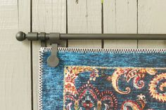 a close up of a blue rug hanging from a metal rod on a wooden wall