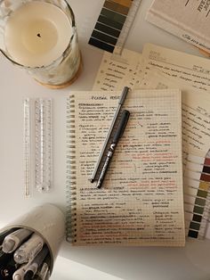 an open notebook sitting on top of a table next to a glass of water and a pen