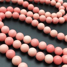 pink and white round beads on a black surface