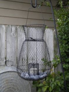 a bird feeder hanging from the side of a wooden fence next to a planter