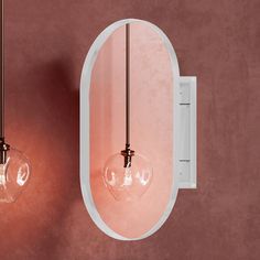 two light bulbs are hanging from the wall in front of a mirror and pink wall