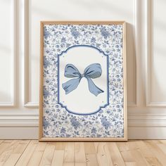 a blue and white frame with a bow on it sitting in front of a wall