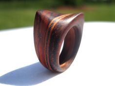 a wooden ring sitting on top of a white table in front of a grass field