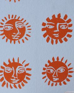 four sun faces drawn on paper with red ink