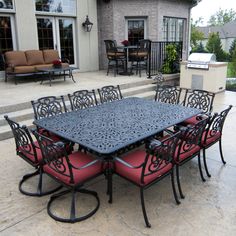 an outdoor dining table and chairs in front of a house